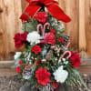 Christmas tree arrangement with red and white flowers, candy canes, and a large red bow
