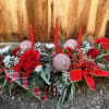 Holiday floral centerpiece with red candles, red flowers, and plaid ribbon