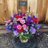 Mixed bouquet of red, pink, and purple flowers in a glass vase