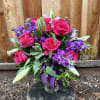 Bouquet of hot pink roses and purple flowers in a glass vase