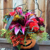 Halloween bouquet in a pumpkin container with pink and orange flowers