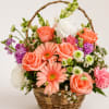 Basket arrangement of coral roses, pink daisies, and white blooms