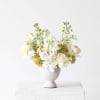White and pale yellow flowers arranged in a gray vase