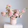 Pink and white flowers arranged in a ribbed blush vase