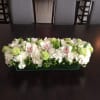 Low rectangular floral arrangement with white orchids, hydrangeas, and green blooms