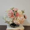 Pink and white floral arrangement in a glass vase on stacked books