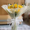 Yellow rose bouquet wrapped in white paper with a ribbon