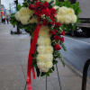 Standing floral cross with red roses and white mums on an easel