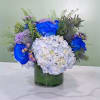 Blue roses and white hydrangeas in a glass vase