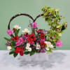 Heart-shaped floral arrangement with pink, red, white, and green blooms in a white box
