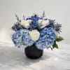 Blue hydrangeas and white roses arranged in a black vase