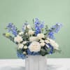 Blue and white floral arrangement in a white container