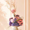 Pink and purple floral arrangement in a pedestal vase with bare branches