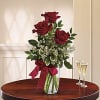 Three red roses in a glass vase with a burgundy ribbon
