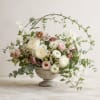 Pastel floral arrangement in a stone urn with arching branches
