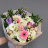 Hand-tied bouquet of pink, white, and purple flowers wrapped in pale paper