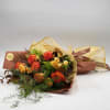 Bouquet of orange and yellow roses wrapped in tan paper