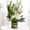 White lilies and roses arranged in a green glass vase
