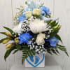 Blue and white floral arrangement in a square vase with ribbon
