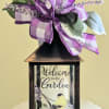 Decorative lantern with a purple ribbon bow and faux greenery