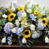 Bright yellow sunflowers set a warm, comforting tone across this elongated casket