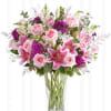 Pink roses and lilies arranged in a clear glass vase