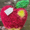 Apple-shaped floral arrangement in pink, green, and yellow with a name tag