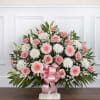 Pink and white floral spray with a pink ribbon on a stand