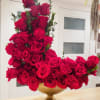 Large arrangement of red roses in a gold vase