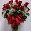 Red roses with baby's breath in a glass vase and red ribbon