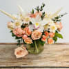 Peach roses and white orchid bouquet in a glass vase
