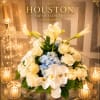 This centerpiece is an elegant, symmetrical floral arrangement featuring a refined palette