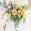 Bouquet of peach, pink, and yellow flowers with trailing greenery