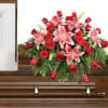 Red roses and pink lilies arranged on a wooden casket