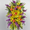 Tall floral standing spray with yellow lilies, orange roses, and purple blooms