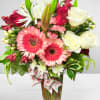 Mixed bouquet of pink gerbera daisies, white roses, and lilies in a vase