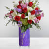 Bouquet of red roses, white lilies, and pink flowers in a purple vase