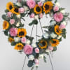Heart-shaped floral wreath with pink roses, sunflowers, and white carnations