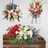 Three floral funeral sprays with red, white, and purple flowers around a casket