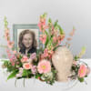 Pink floral arrangement with a framed portrait and urn