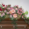 Floral spray of pink and red flowers on a wooden casket