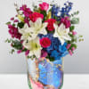 Bouquet of pink roses, white lilies, and blue hydrangeas in a glass vase