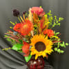 Bright mixed bouquet with a sunflower in a red glass vase