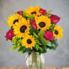 Bouquet of yellow sunflowers and pink roses in a clear glass vase