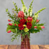 Deep crimson roses meet sculptural pink protea in this July birthday arrangement