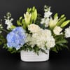 White and blue floral arrangement in a white ceramic vase