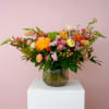 Mixed bouquet of orange, pink, and white flowers in a ribbed glass vase