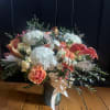 Peach and white floral arrangement in a glass vase with a ribbon