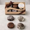 Box of chocolate-covered Oreos with a ribbon, shown with four cookies outside the box.