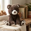 Brown teddy bear plush sitting on a blanket in a nursery-like room